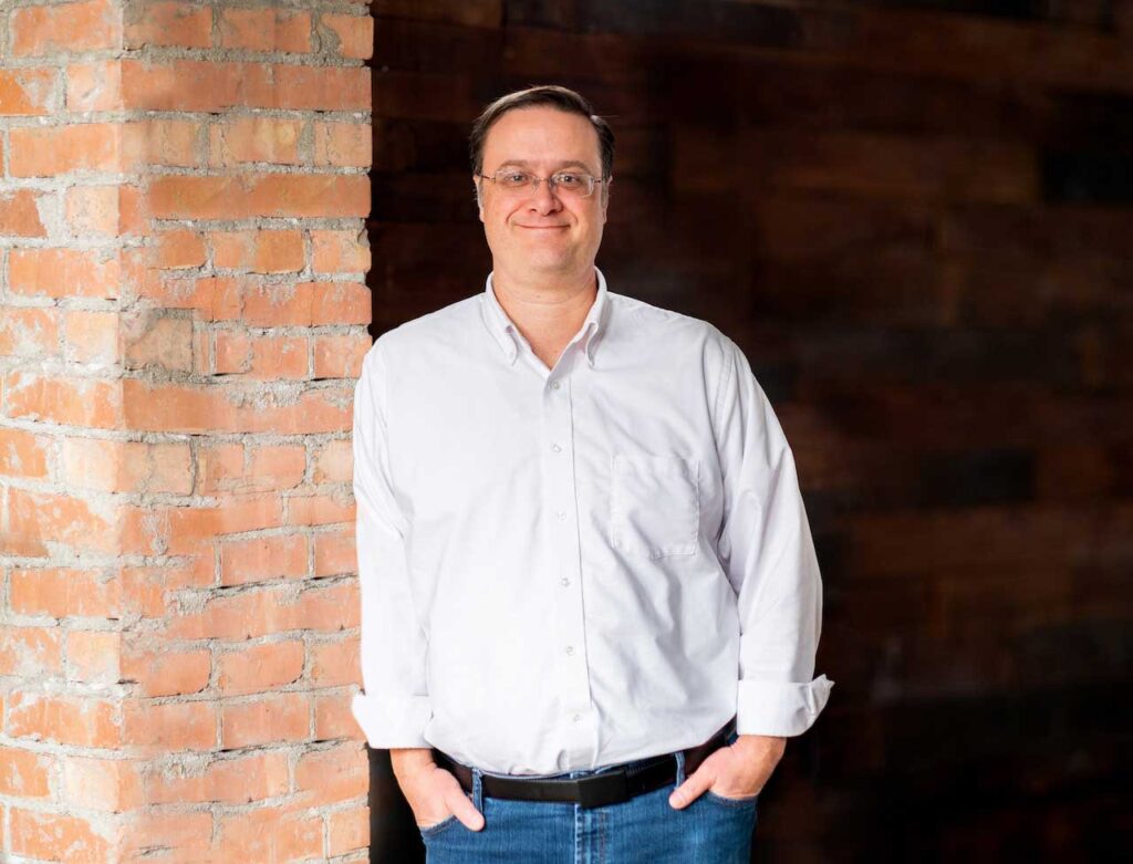 Kenneth Prigmore standing beside a brick column